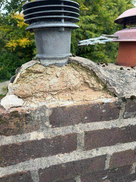 Crumbling mortar round the flue terminal on the weathered stack