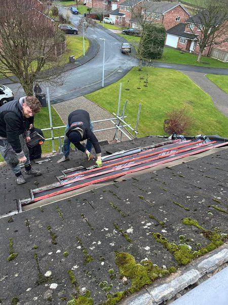 Fixing battens near the ridge, tiles stacked clear on the boards