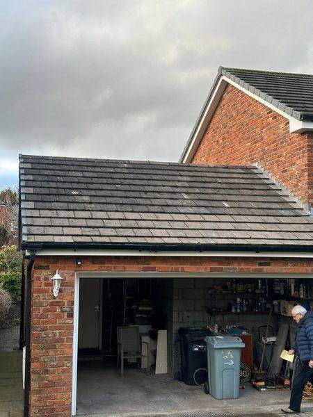 The attached garage roof from the drive, plain tiles running up to the house wall