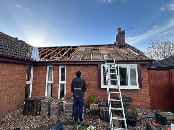 Bare rafters after the strip, old tiles stacked out on the garden