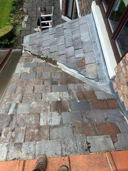 Down the slope, with a colleague steadying the ladder at the eaves
