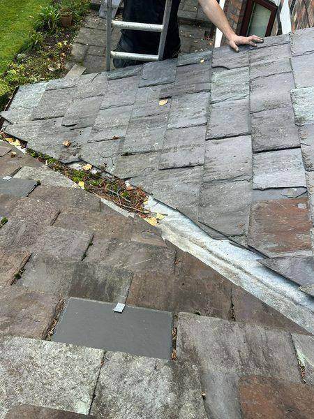 A replacement slate slid home by hand into a standing course