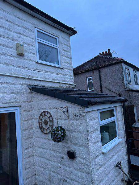 The kitchen roof from the yard, dark covering against white render